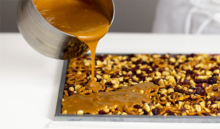 Pouring caramel sauce over nuts and dried fruits.