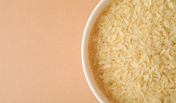 raw rice in a white bowl on a peach background