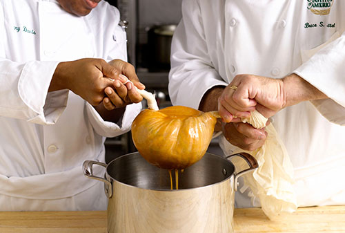 Straining a bisque through cheesecloth