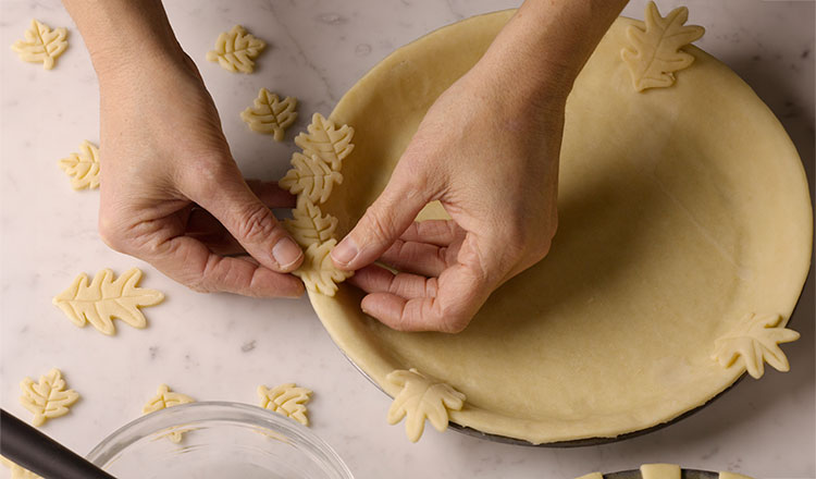 Decorating pie crust with cut-out pie-crust leaves