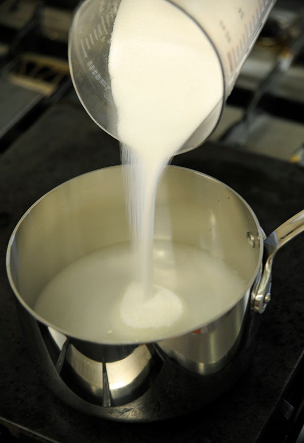 Pouring sugar into water before caramelizing.