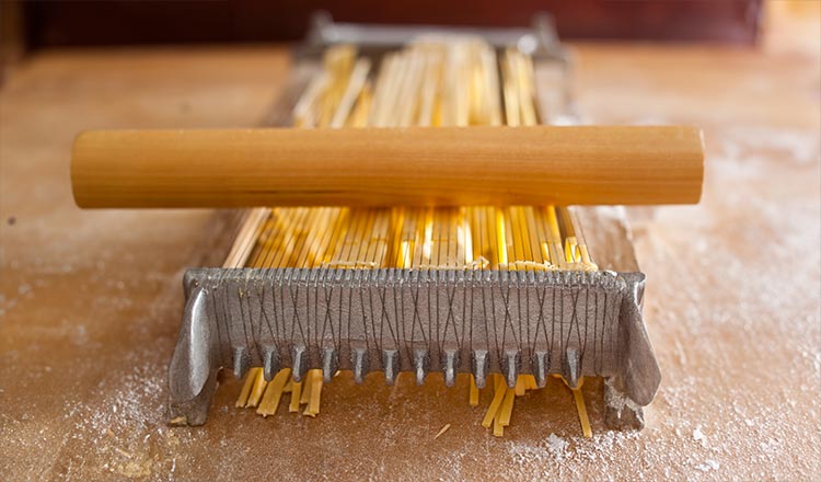 Making homemade macaroni with a traditional chitarra wire cutter